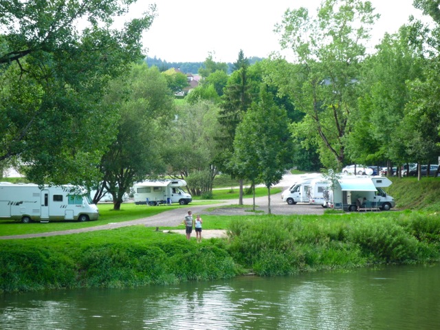 a body of water surrounded by green grass and trees