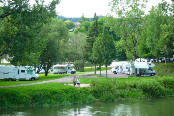 a body of water surrounded by green grass and trees